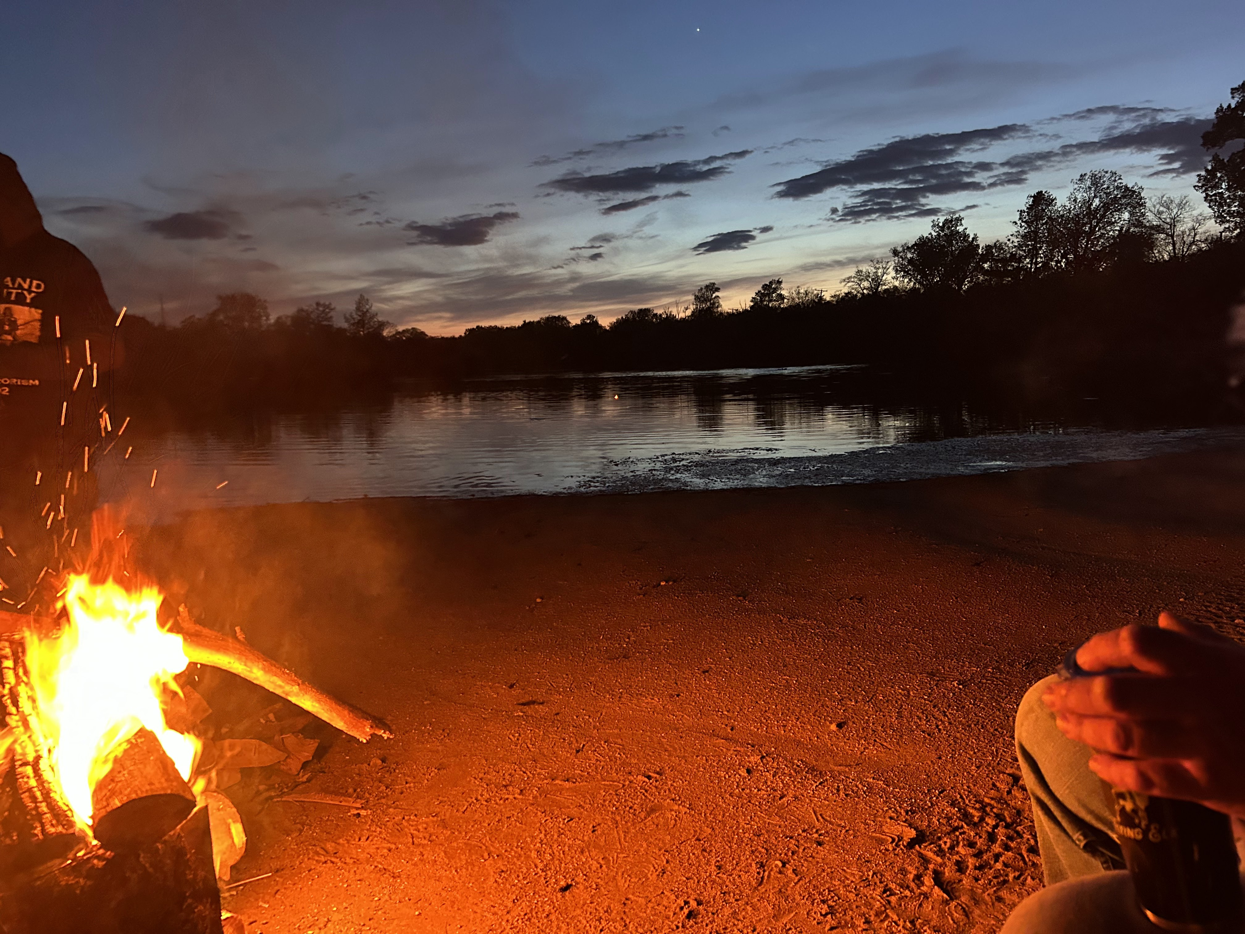 Campfire glowing on the beach at dusk beside Deer Creek Lake in Plainfield Illinois