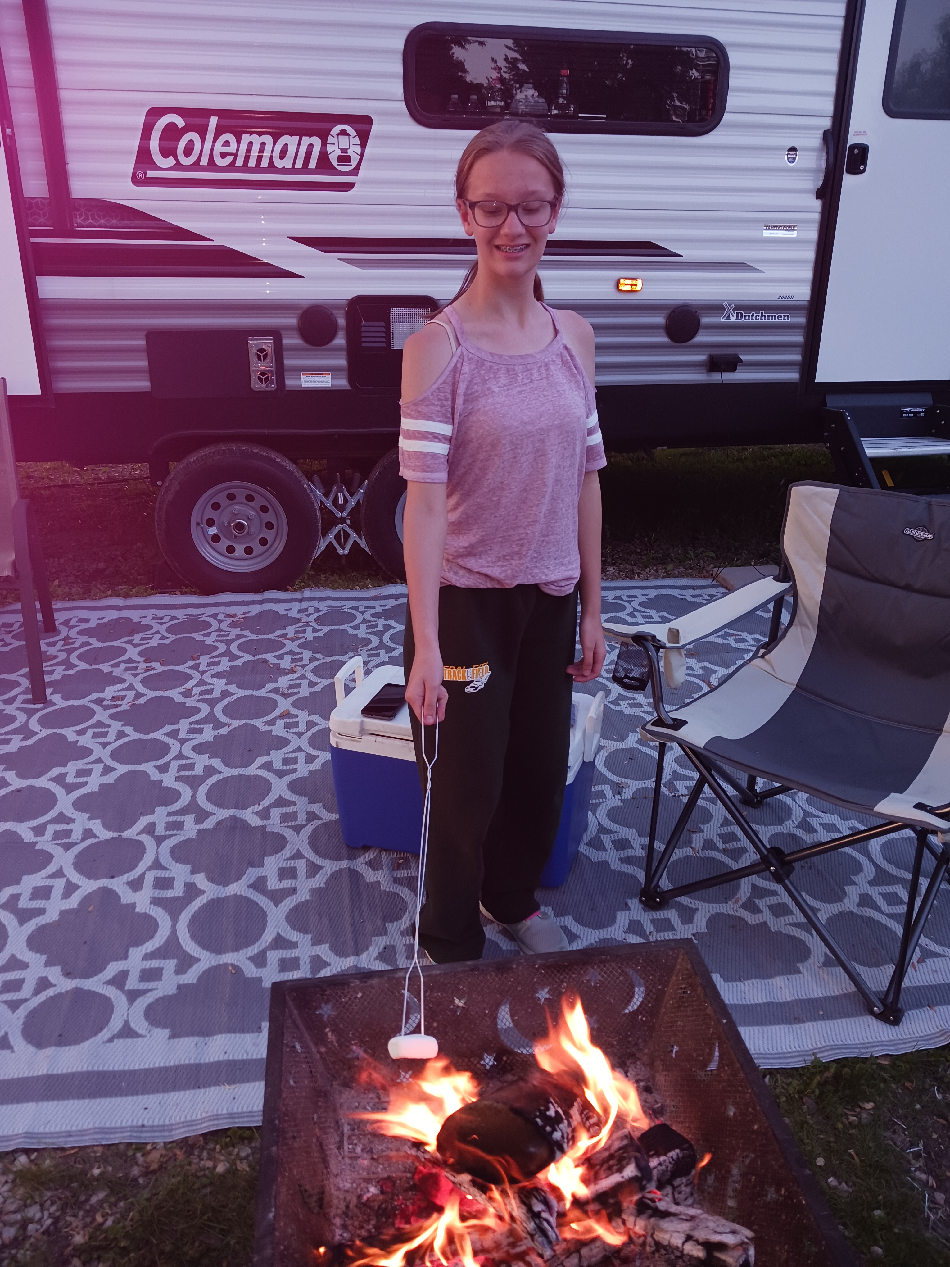 Young girl roasting marshmallows over a campfire at her RV site at Deer Creek Recreation Club