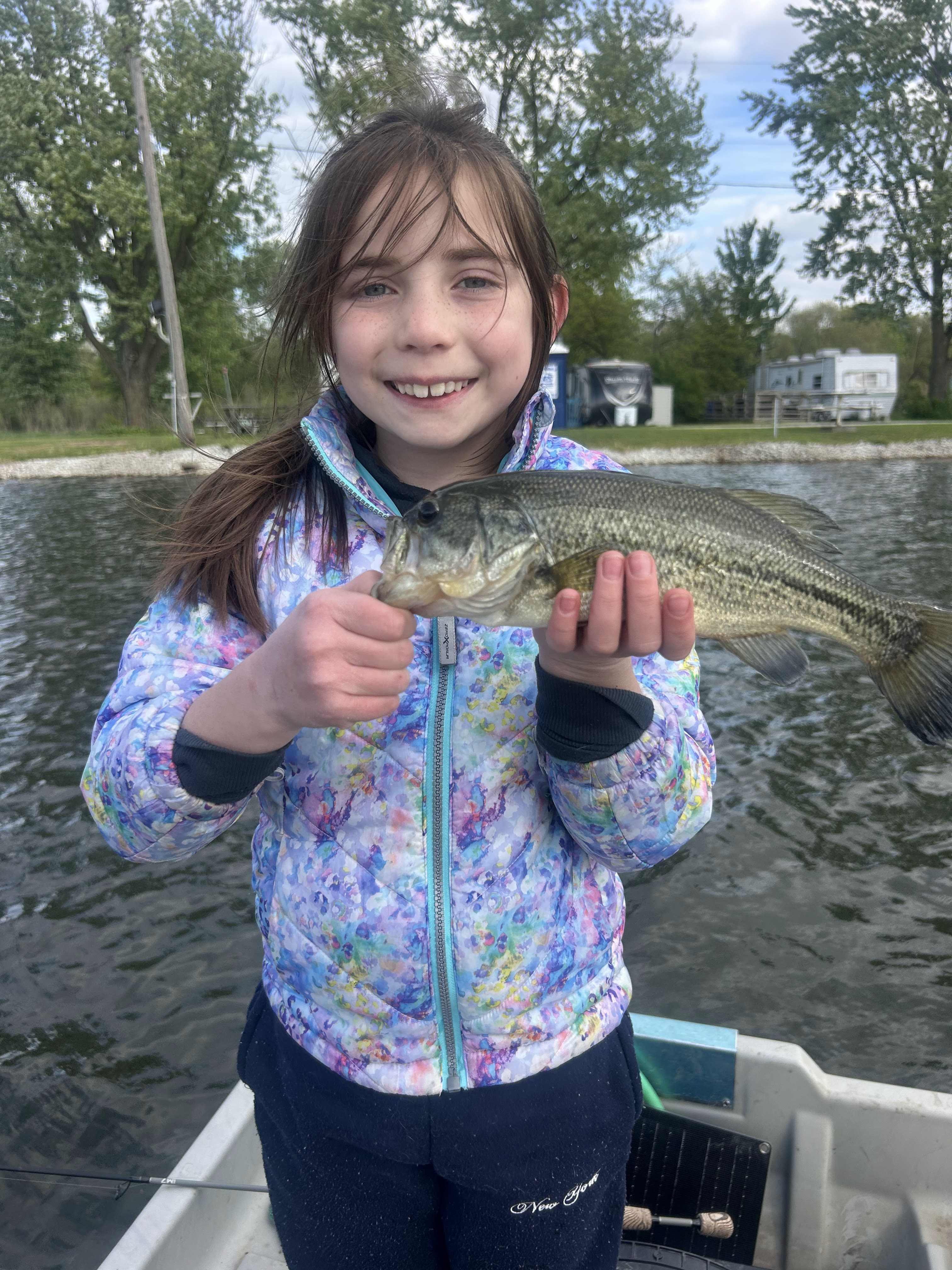 Young girl on a boat holding a large trophy bass caught on Deer Creek Lake in Illinois