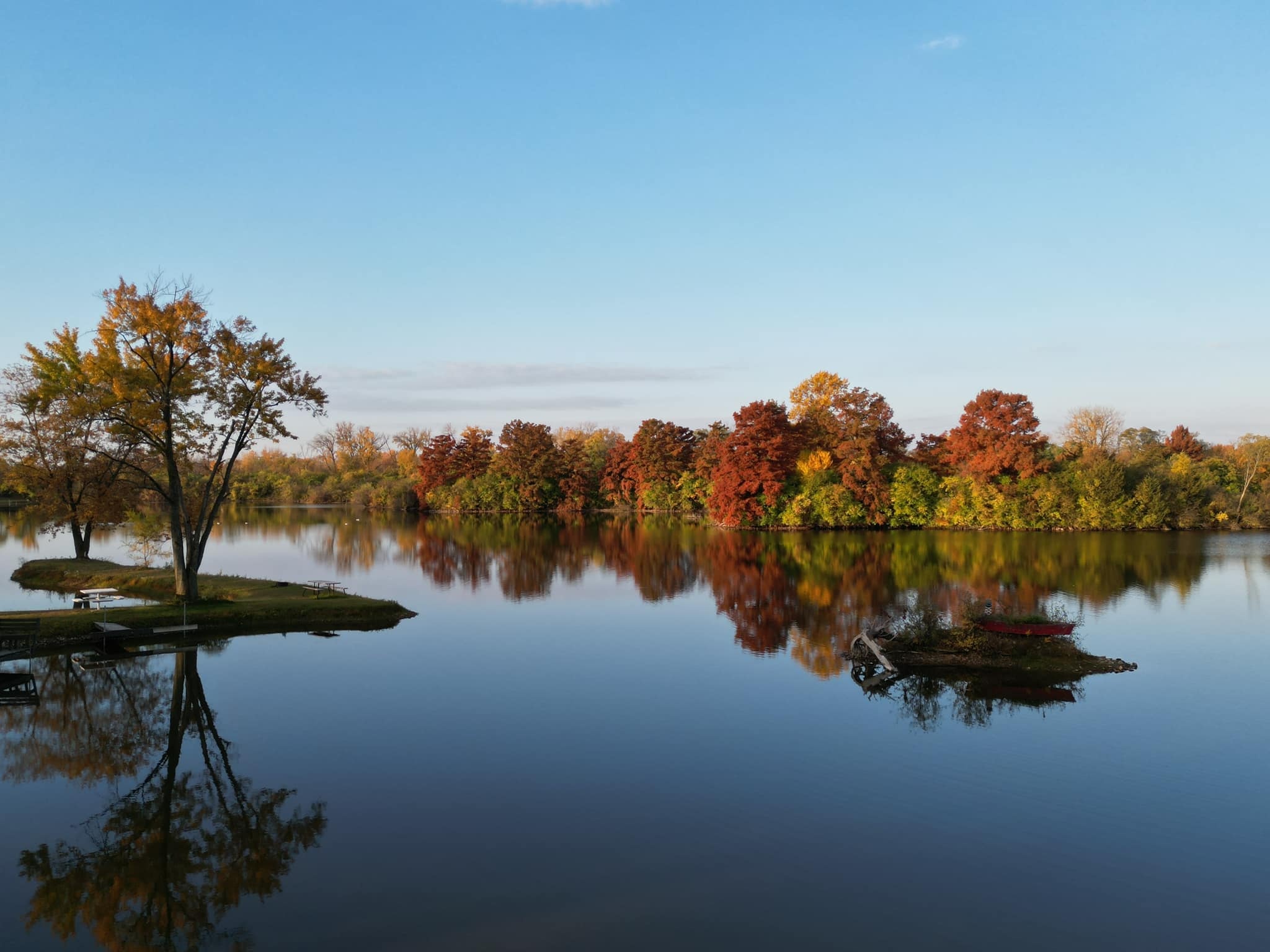 Deer Creek Lake in peak fall color with brilliant autumn foliage reflecting on perfectly still water at Deer Creek Recreation Club in Plainfield, Illinois