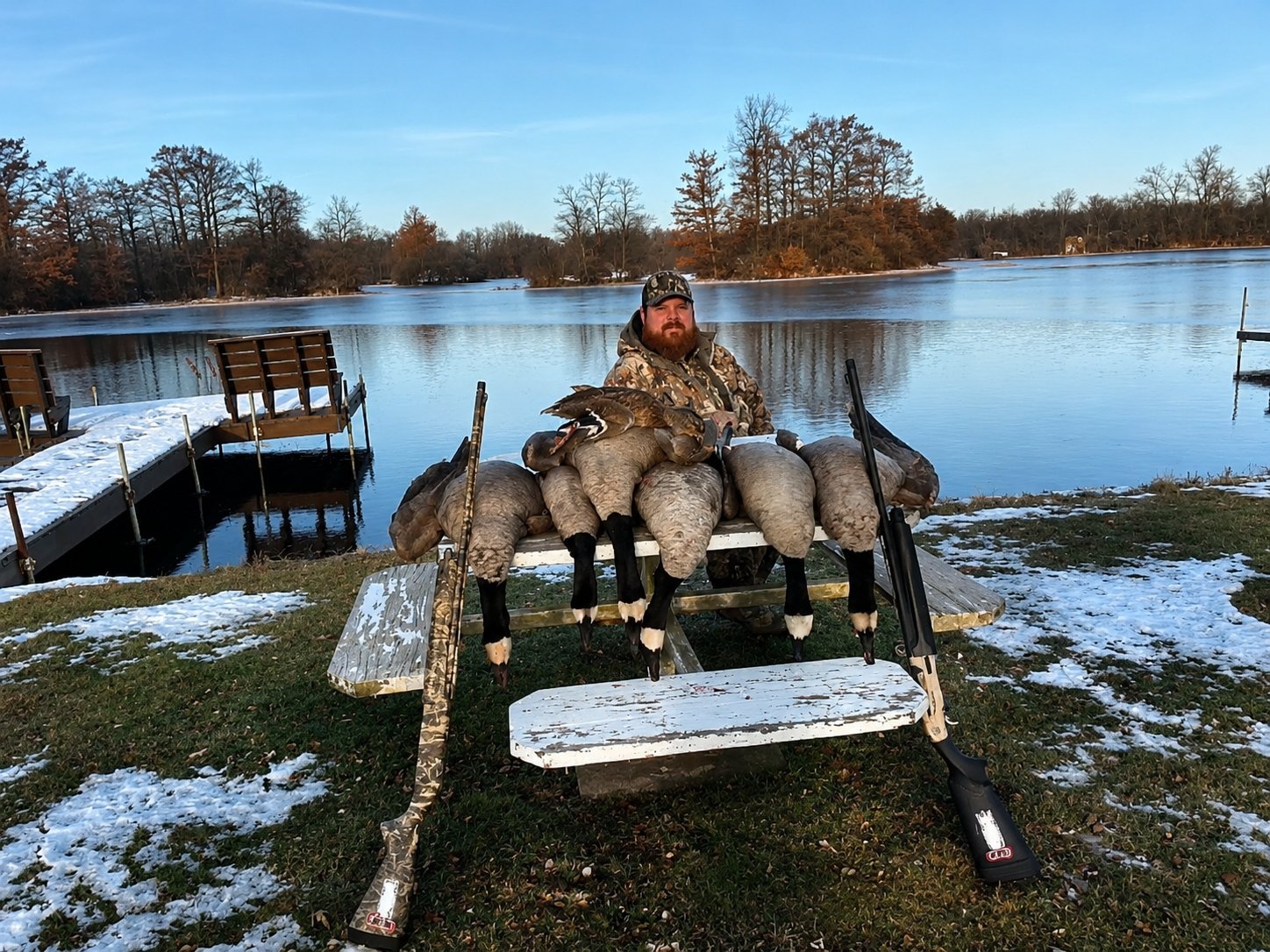 Deer Creek Recreation Club member with a full Canada goose harvest displayed on a picnic table by the frozen lake and dock