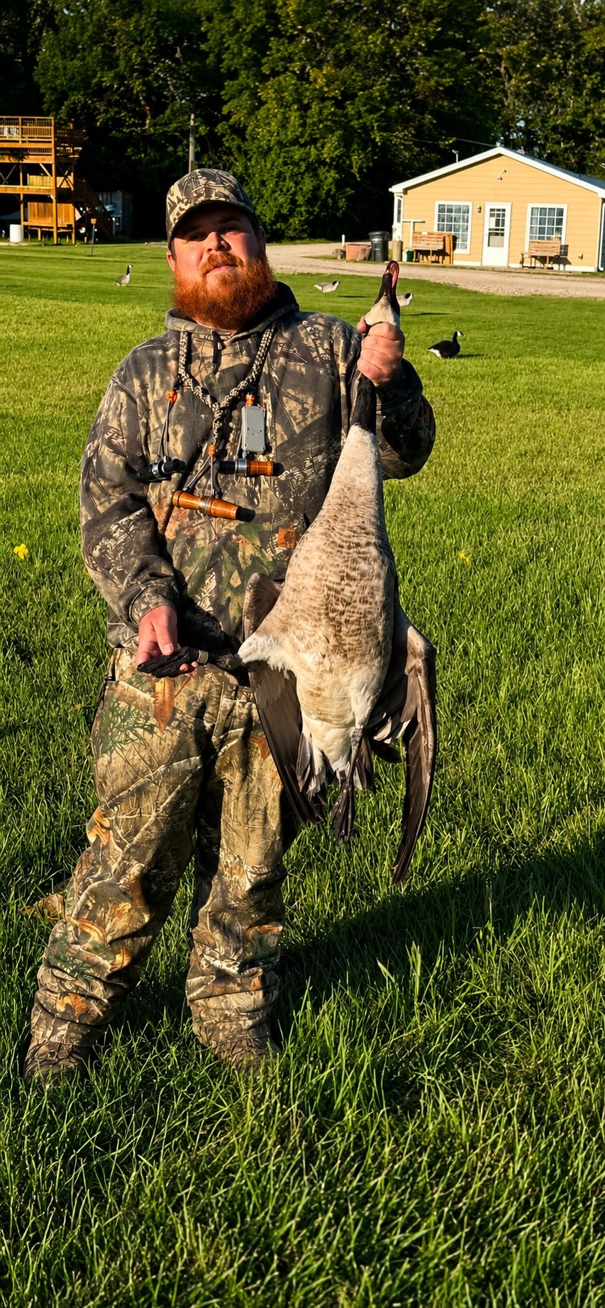 Deer Creek Recreation Club member holding a harvested Canada goose on the club grounds near the clubhouse in summer