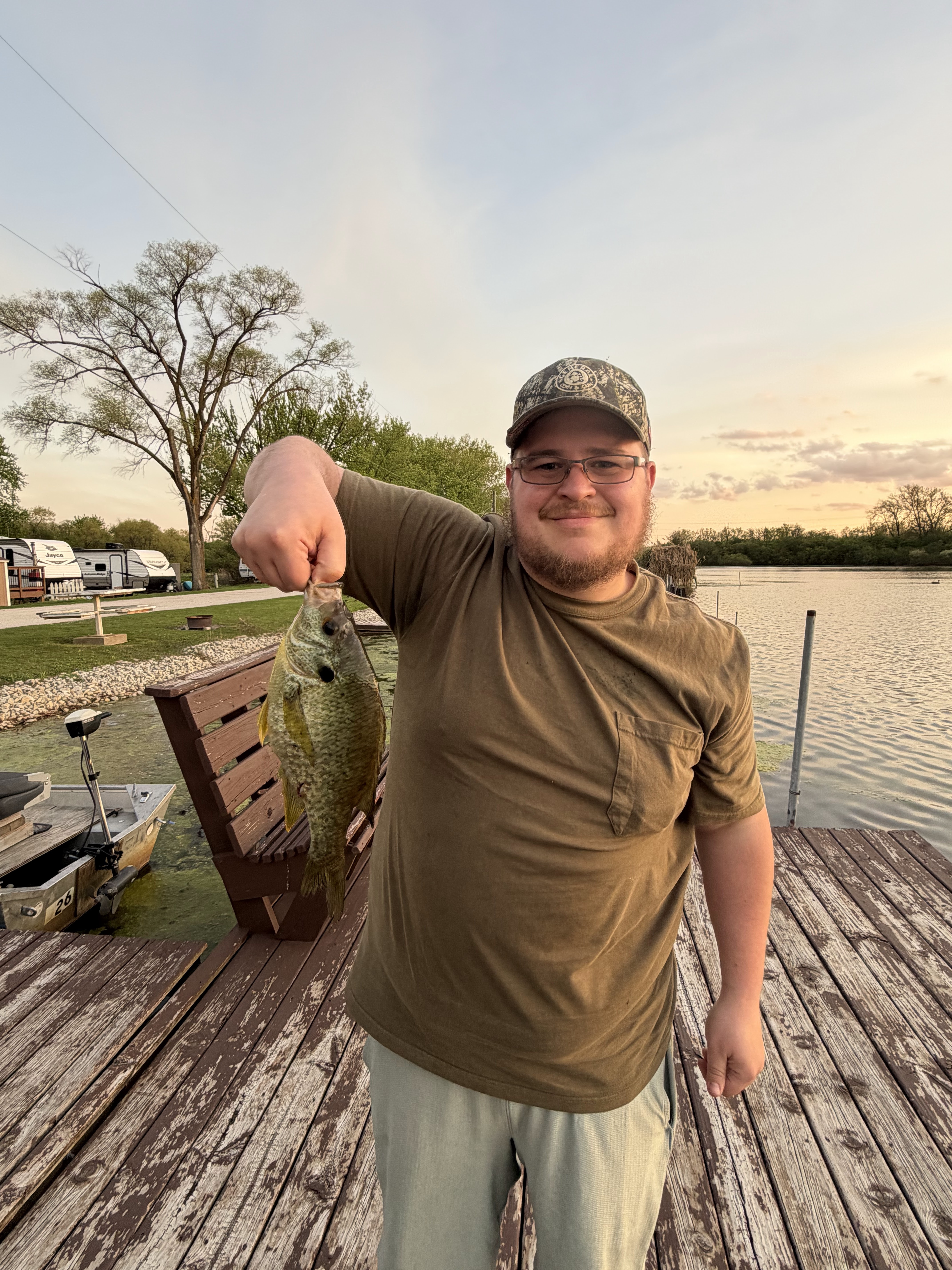 Deer Creek member holding a crappie caught from the dock at sunset on the lake
