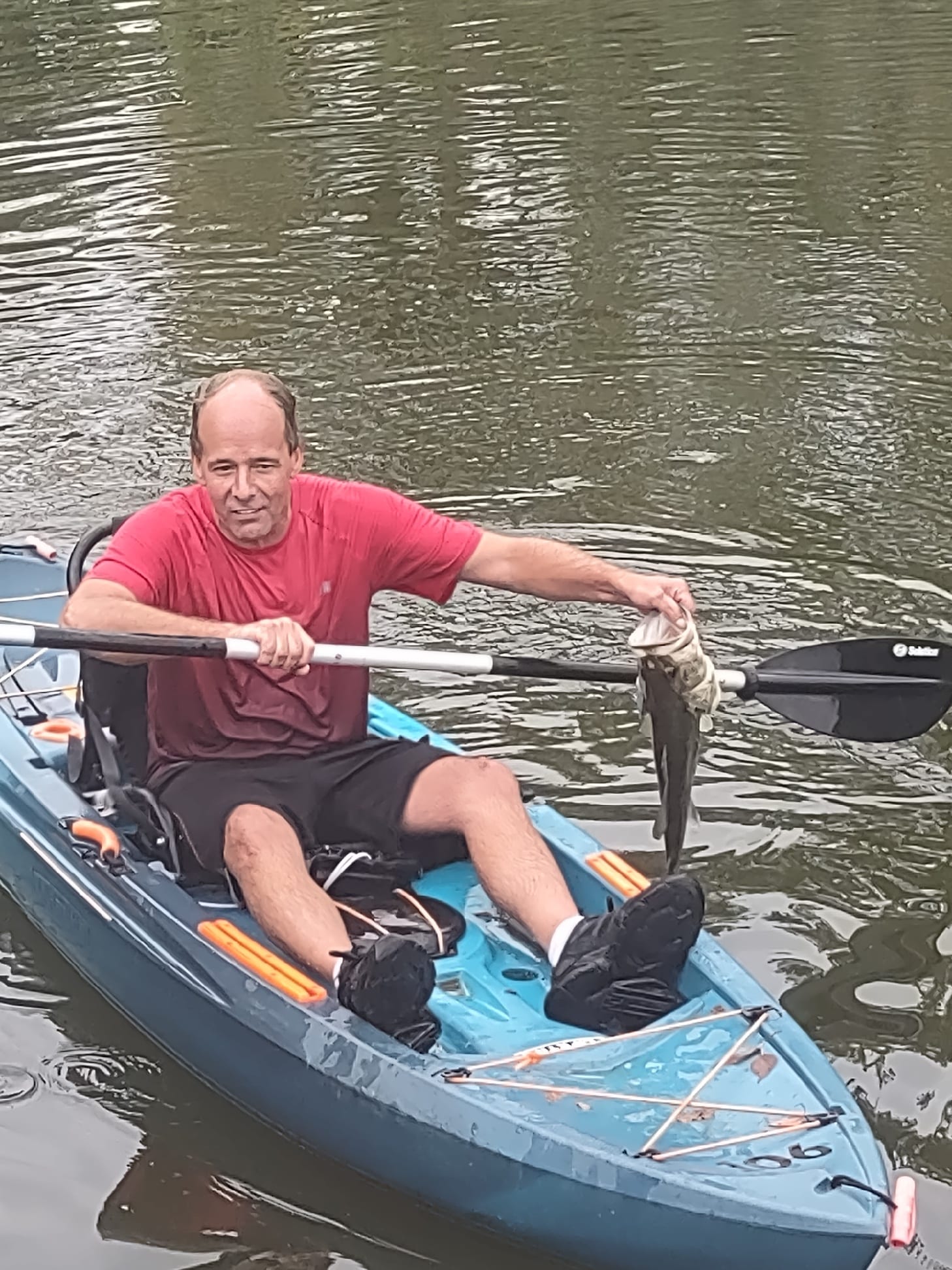 Club member kayak fishing on Deer Creek Lake holding a bass catch