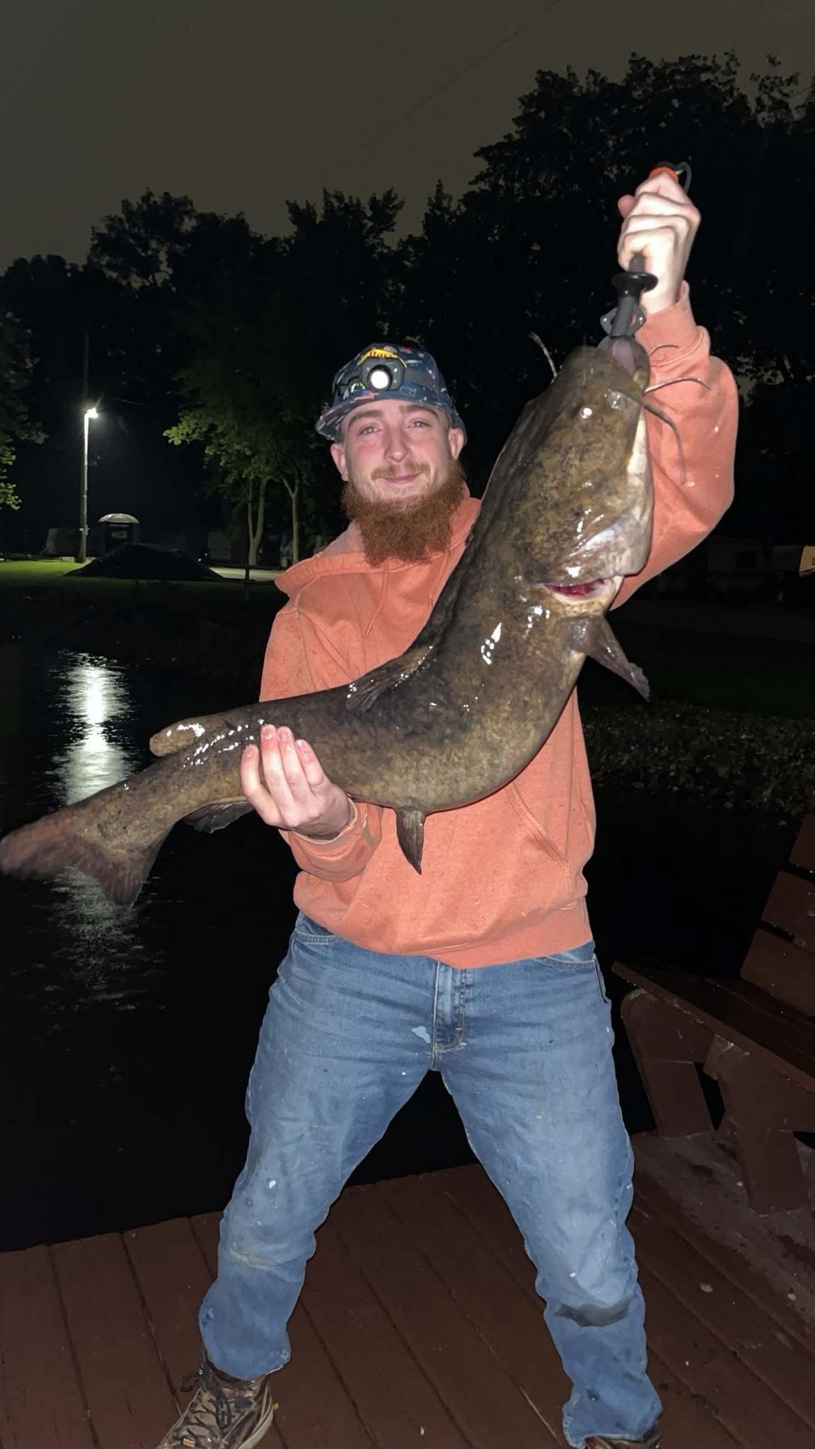 Deer Creek Recreation Club member holding a large flathead catfish caught night fishing from the dock