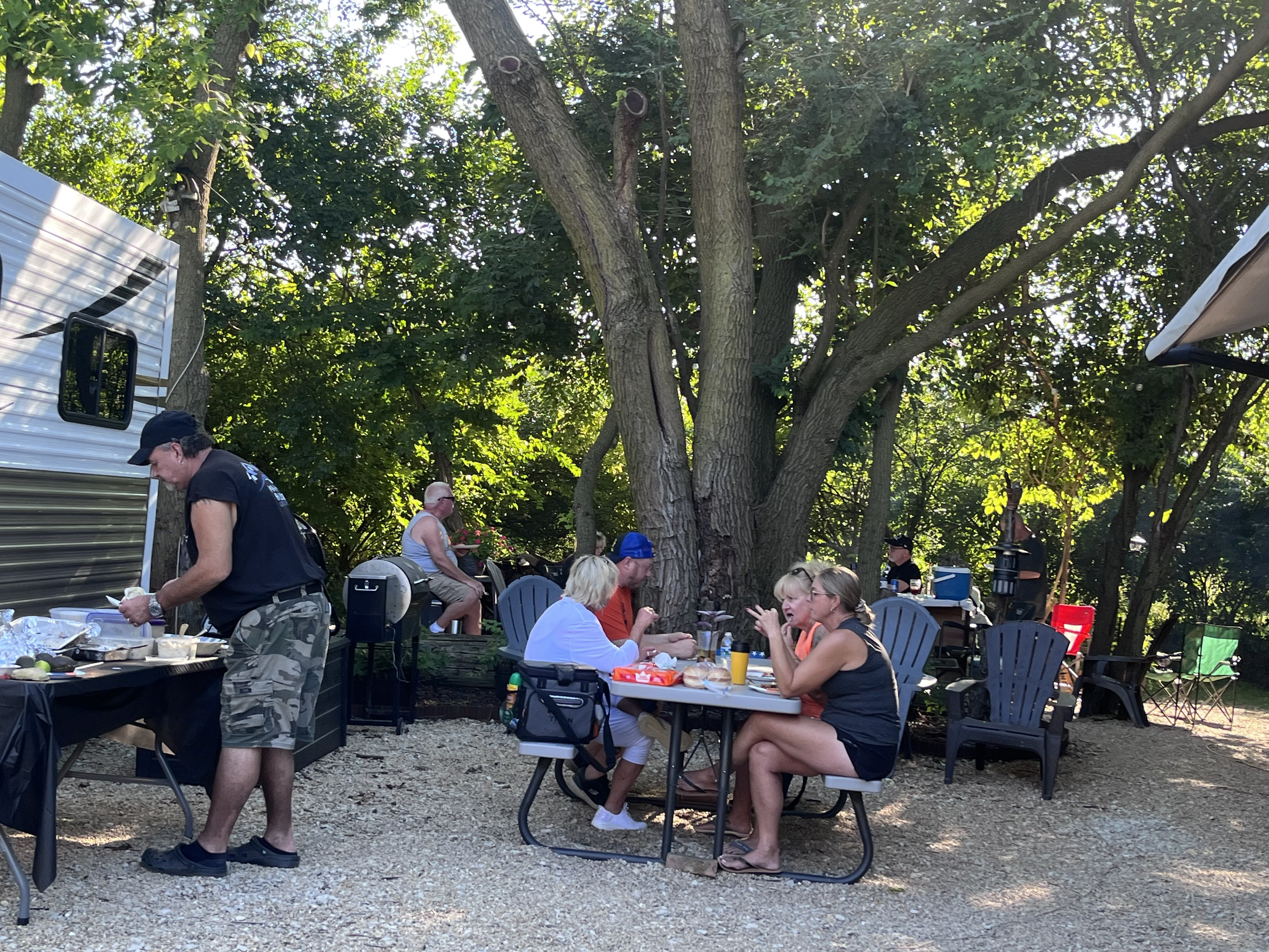 Deer Creek Recreation Club members eating and relaxing at a shaded campsite in summer