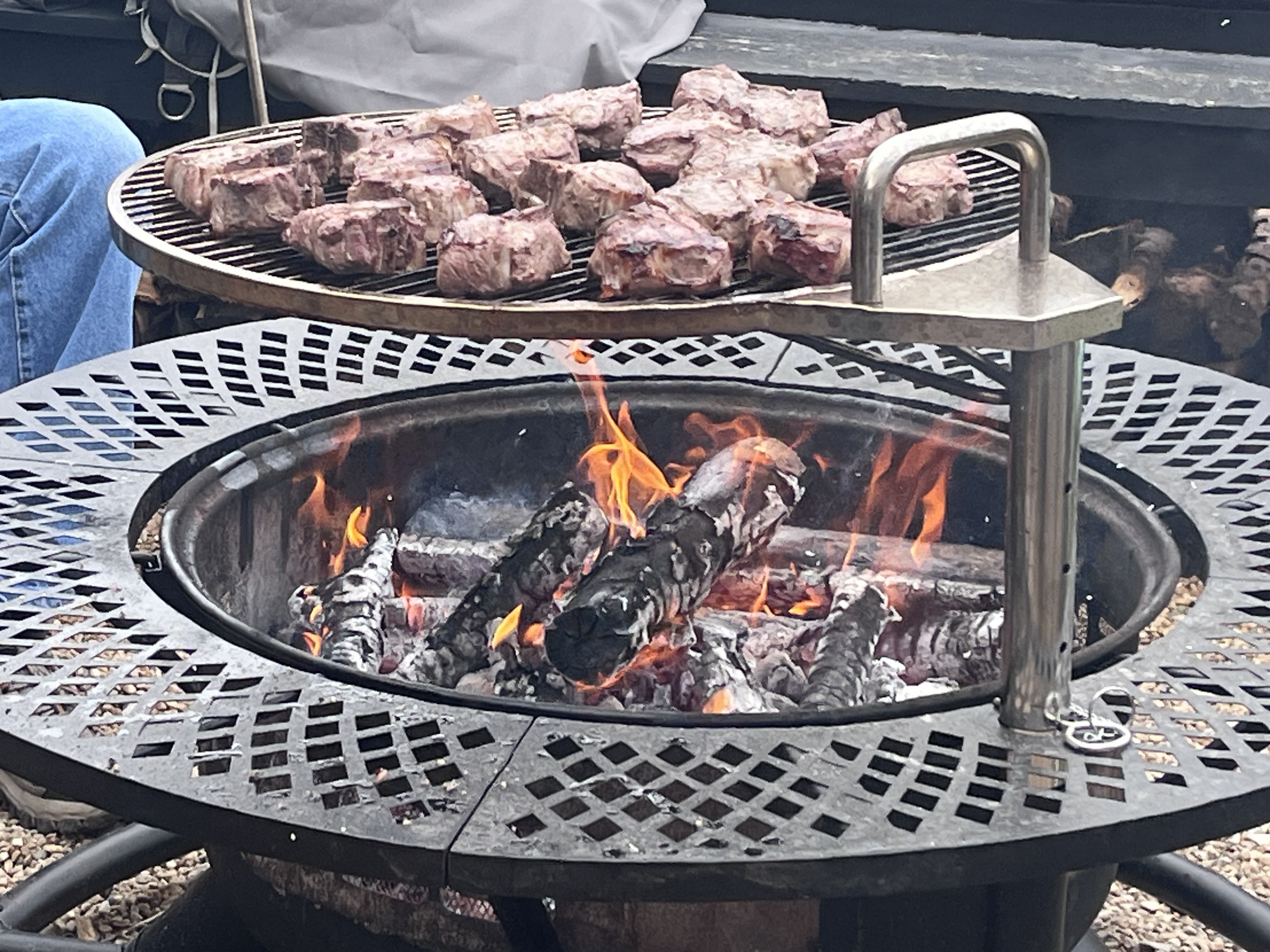 Steaks grilling over an open campfire at a Deer Creek Recreation Club social cookout event