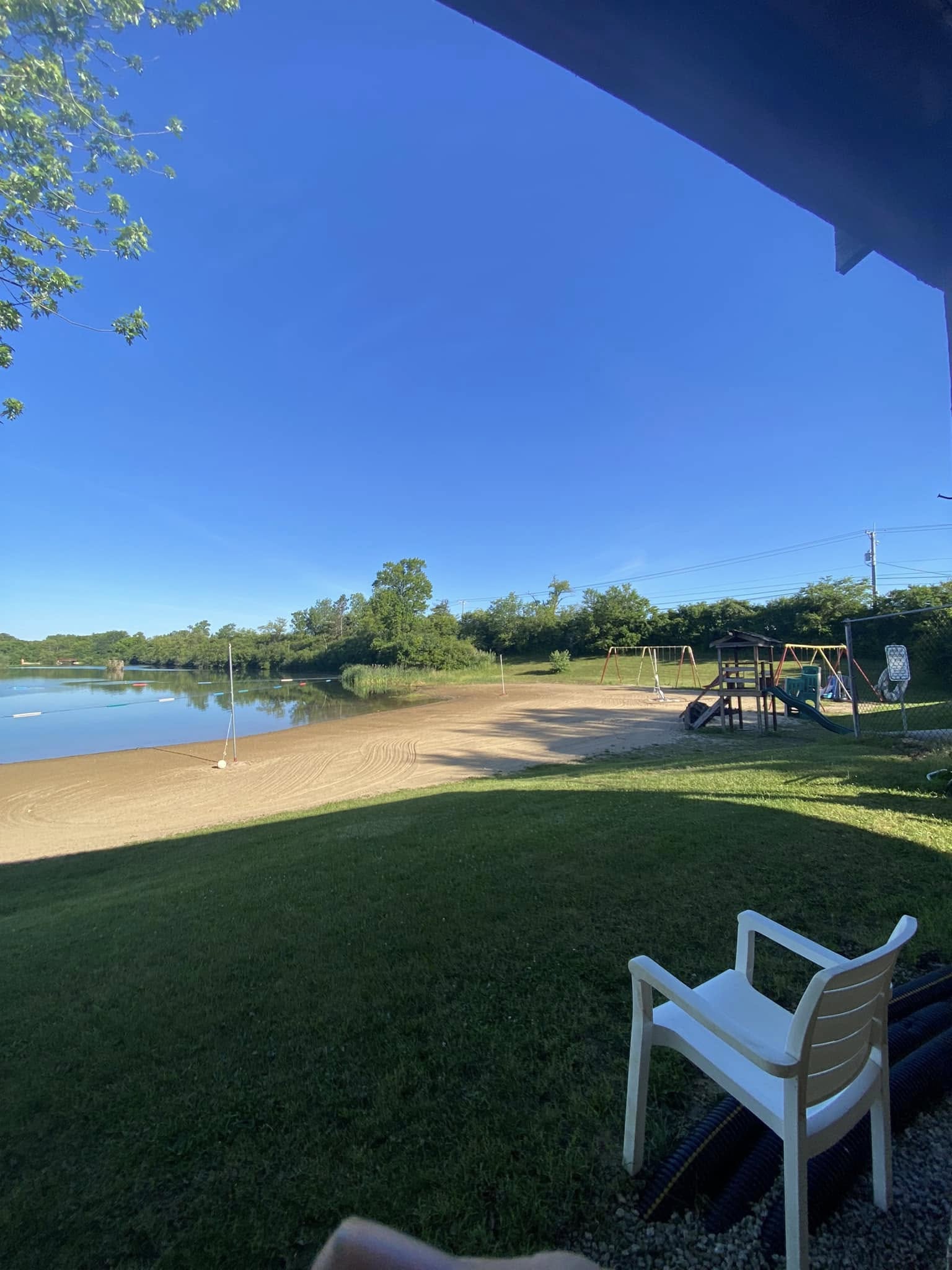 Deer Creek Recreation Club private sandy beach with playground equipment and swimming area on a clear summer day