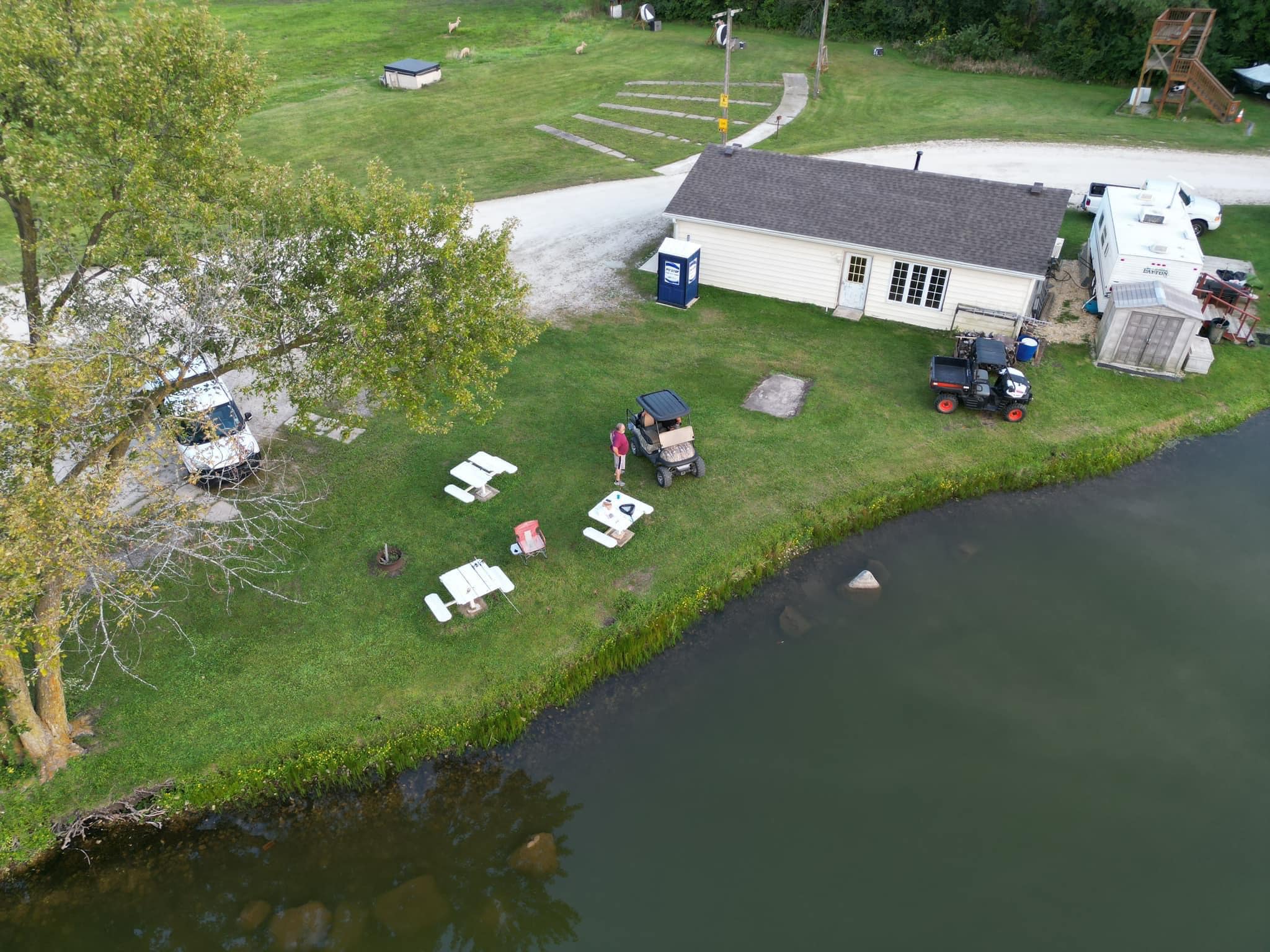 Aerial drone view of Deer Creek Recreation Club showing the clubhouse, sandy beach, and lake shoreline in Plainfield Illinois