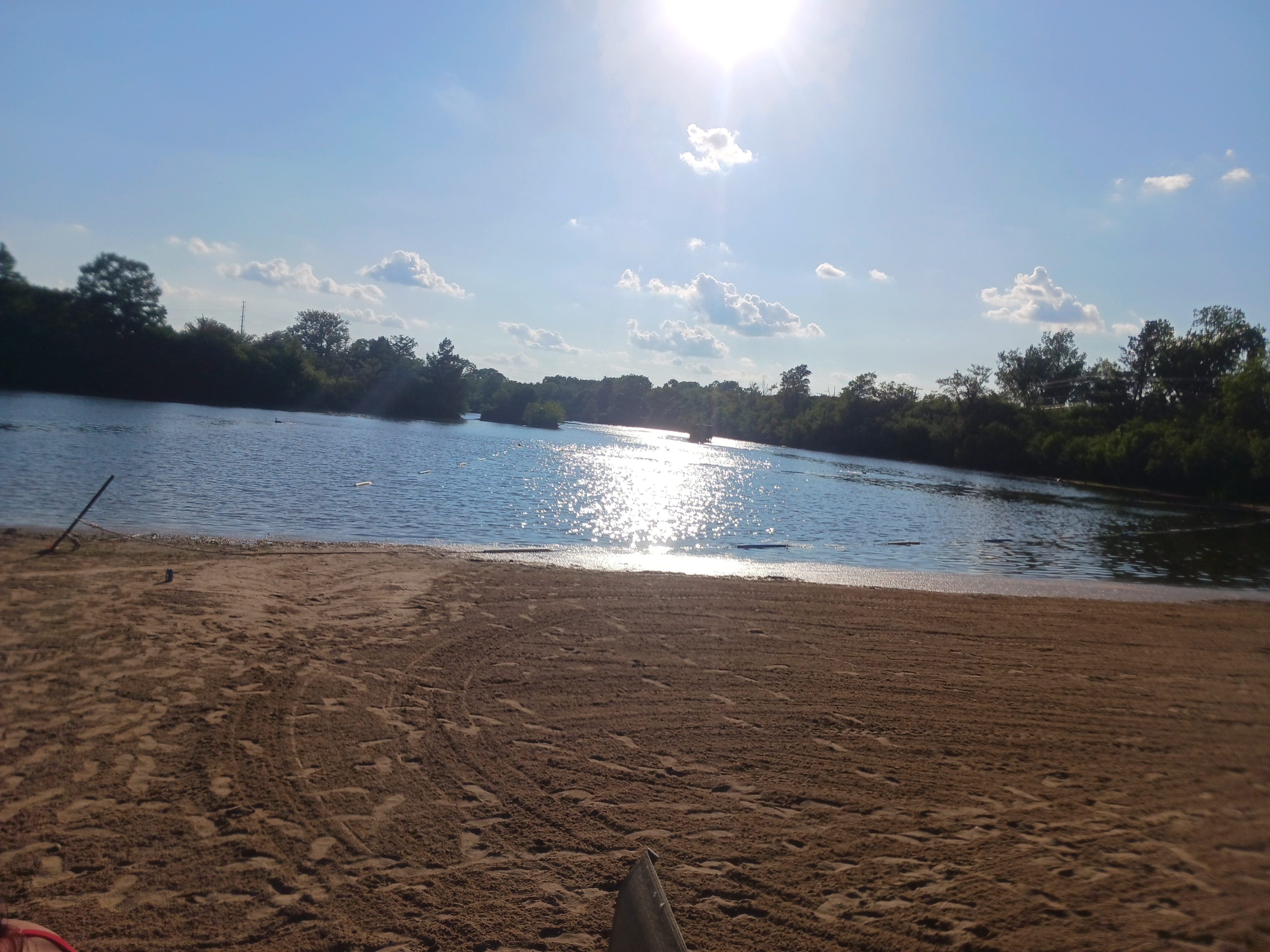 Wide view of the Deer Creek Recreation Club private sandy beach and lake on a sunny day