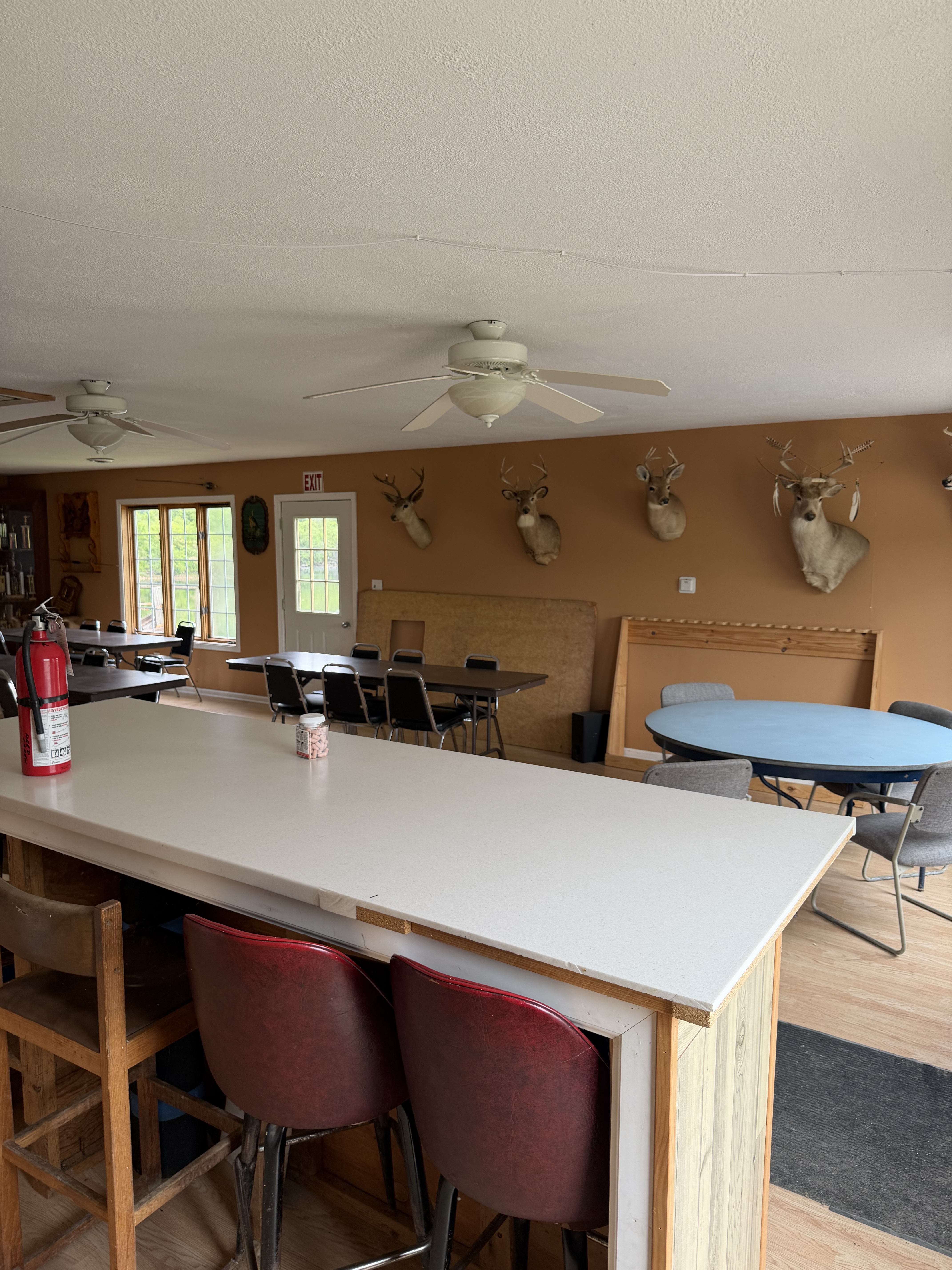 Deer Creek Recreation Club Trap House interior showing the bar area, deer and buck trophy mounts on the wall, and gathering tables